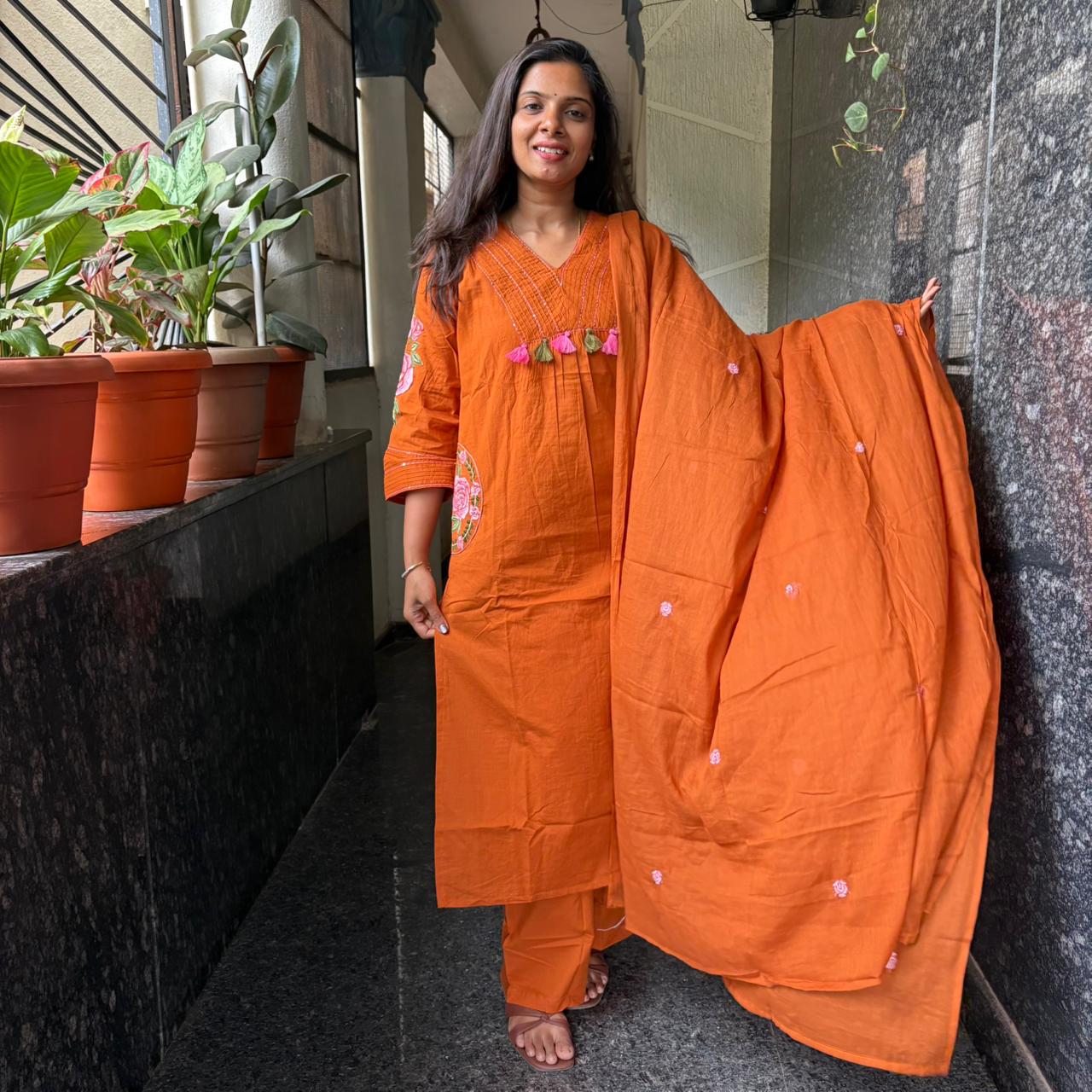 Close-up of pink rose embroidery on orange cotton kurta sleeve
